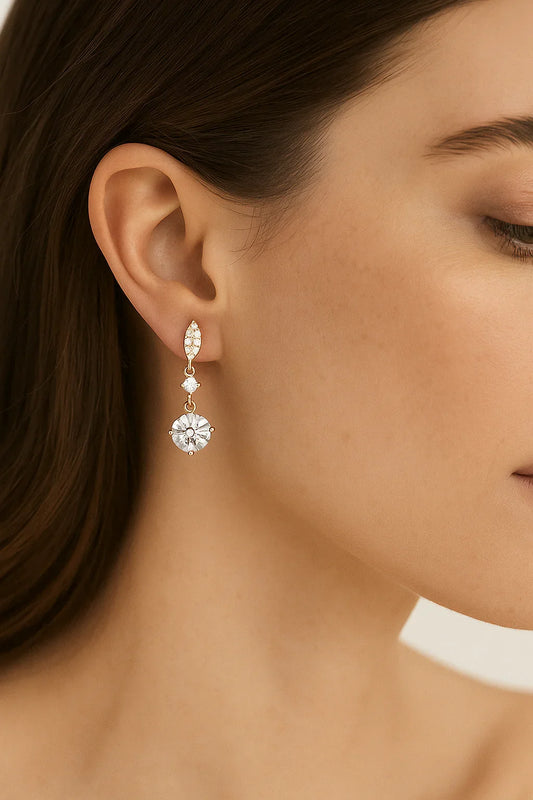 Gold drop earring with clear gemstones worn on a woman's ear, elegant jewelry style