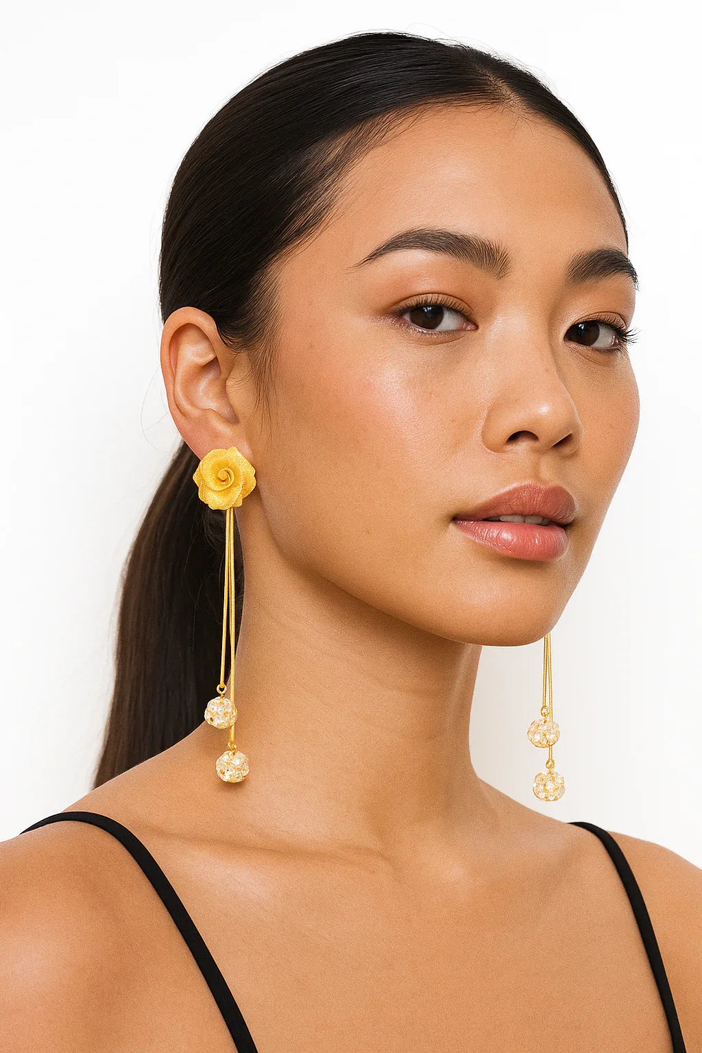 Woman wearing long gold floral statement earrings with crystal bead accents