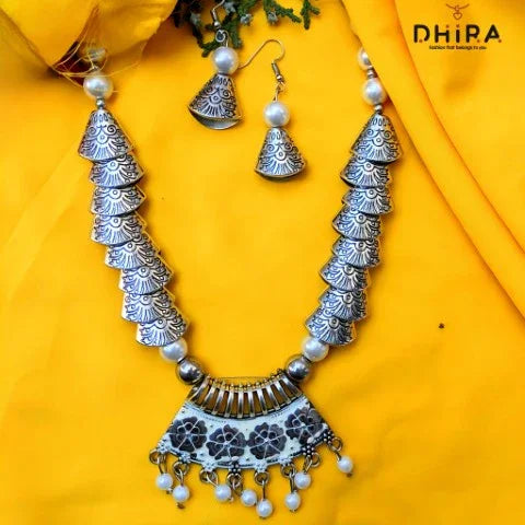 Oxidized silver statement necklace and earrings set with floral motifs on yellow fabric