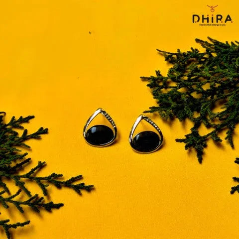 Elegant black stone stud earrings with silver accents on yellow background, jewelry display