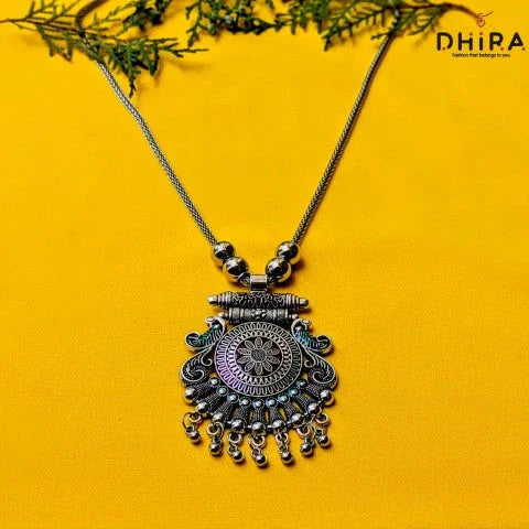 Oxidized silver necklace with intricate pendant and beads on yellow background