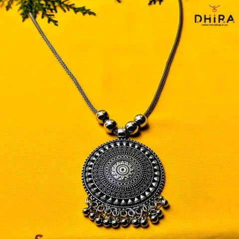 Oxidized silver statement necklace with large circular pendant on yellow background