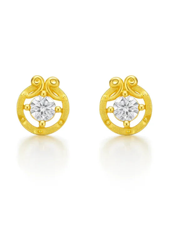 Gold stud earrings with circular design and clear gemstone center on white background