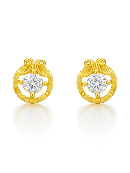 Gold stud earrings with circular design and clear gemstone center on white background