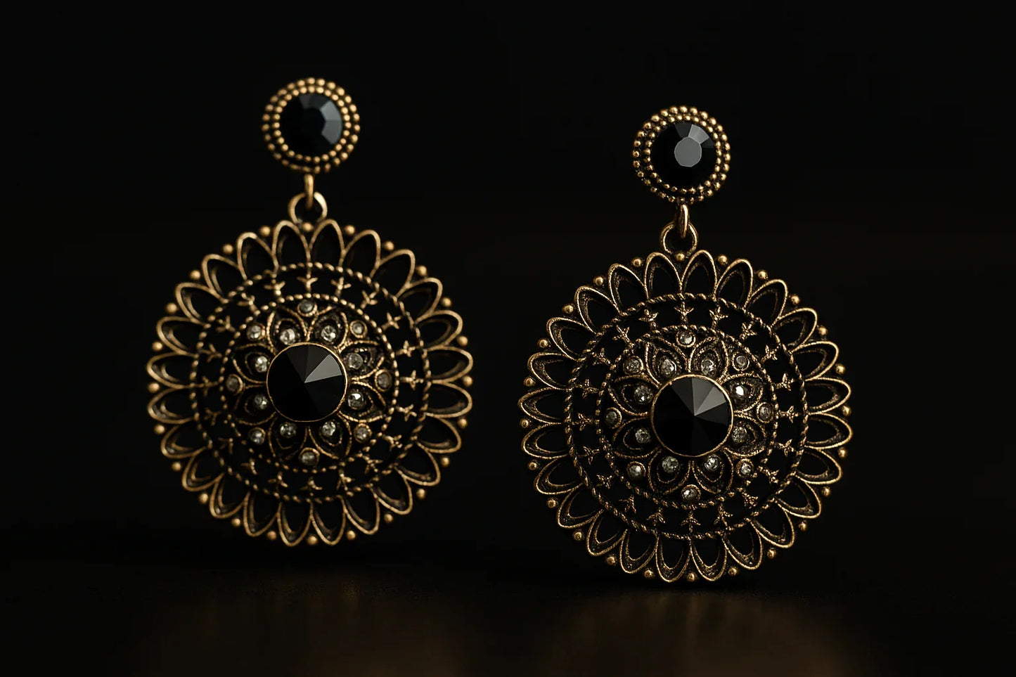 Vintage gold filigree dangle earrings with black gemstone center on black background